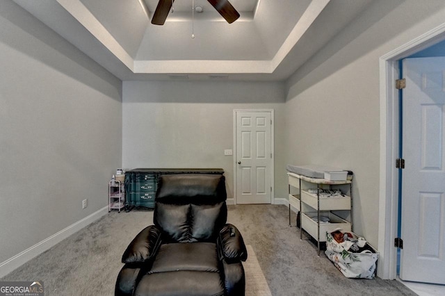 living area featuring a tray ceiling, ceiling fan, baseboards, and carpet floors