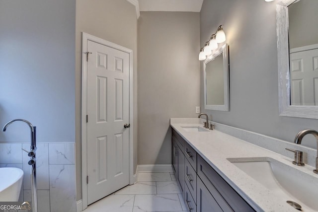 bathroom featuring a freestanding bath, double vanity, marble finish floor, and a sink