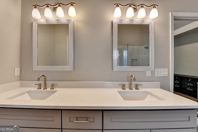 full bathroom with a stall shower, double vanity, and a sink