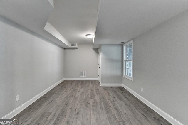 below grade area featuring wood finished floors, baseboards, and visible vents