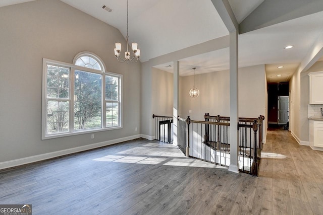 unfurnished dining area with light wood-style floors, a healthy amount of sunlight, a notable chandelier, and visible vents