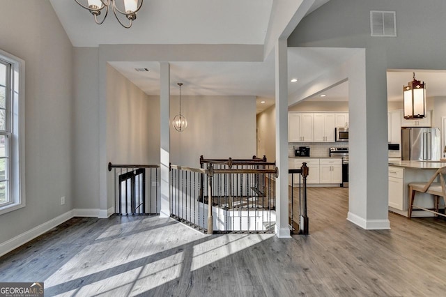 entryway featuring a chandelier, wood finished floors, baseboards, and visible vents