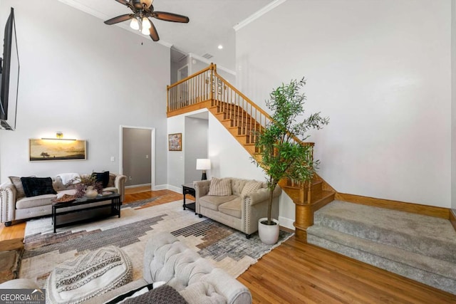 living room with crown molding, a ceiling fan, stairway, wood finished floors, and baseboards