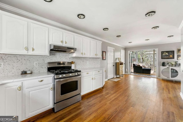 kitchen with stainless steel gas stove, under cabinet range hood, wood-type flooring, and ornamental molding