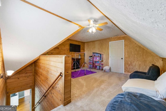 additional living space featuring lofted ceiling, a textured ceiling, wood walls, ceiling fan, and carpet