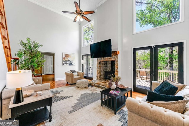 living room with ornamental molding, a high ceiling, wood finished floors, and a fireplace