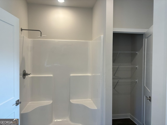 bathroom with a spacious closet and walk in shower