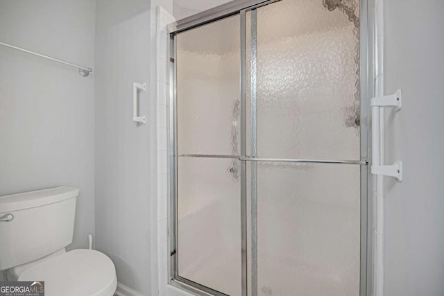 bathroom featuring toilet and a shower stall
