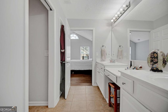 ensuite bathroom featuring ensuite bathroom, tile patterned flooring, a sink, double vanity, and baseboards
