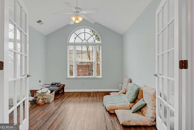 sitting room featuring ceiling fan, vaulted ceiling, visible vents, wood finished floors, and french doors