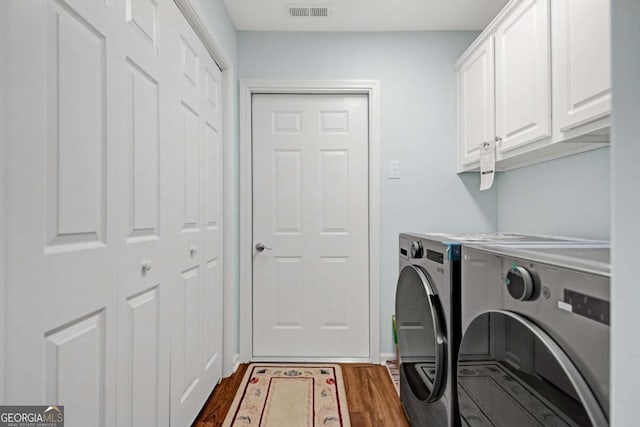 washroom featuring washer and dryer, dark wood-type flooring, visible vents, and cabinet space