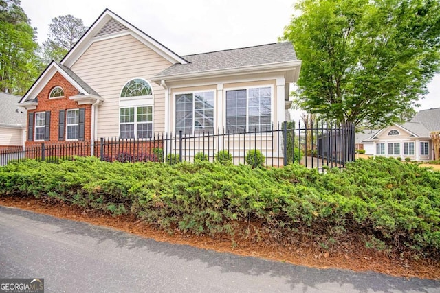 view of front facade with brick siding and fence