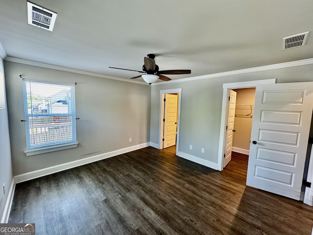 1037 E Doyle St, Toccoa, GA 30577 - unfurnished bedroom featuring dark wood-style flooring, ornamental molding, a walk in closet, a closet, and a ceiling fan