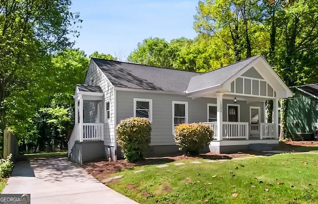 view of front of home featuring a shingled roof, driveway, a front lawn, and covered porch
