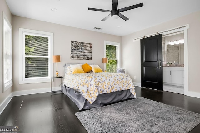 bedroom featuring visible vents, baseboards, a barn door, and wood finished floors