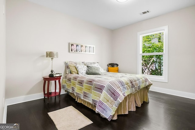 bedroom featuring visible vents, baseboards, and wood finished floors
