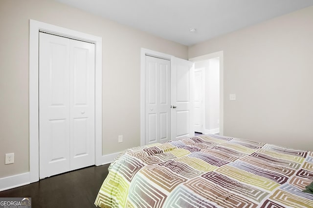 bedroom featuring baseboards, dark wood-style floors, and multiple closets