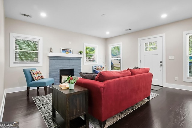 living area with baseboards, recessed lighting, dark wood-style floors, a brick fireplace, and visible vents
