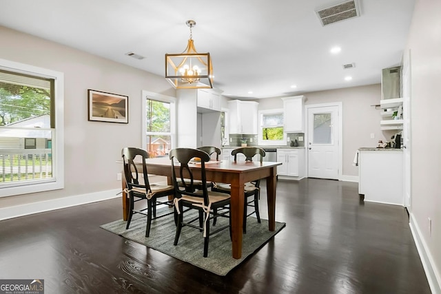 dining room featuring a notable chandelier, dark wood-type flooring, visible vents, and baseboards