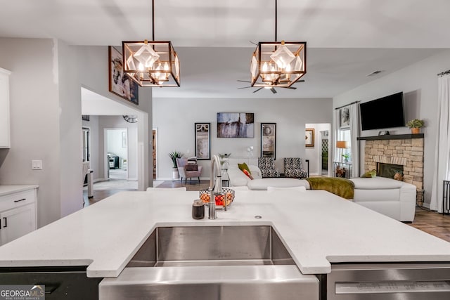 kitchen featuring an inviting chandelier, open floor plan, a sink, and dishwashing machine
