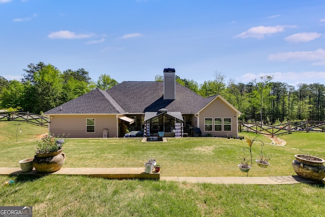 rear view of house featuring fence, a lawn, a chimney, and roof with shingles