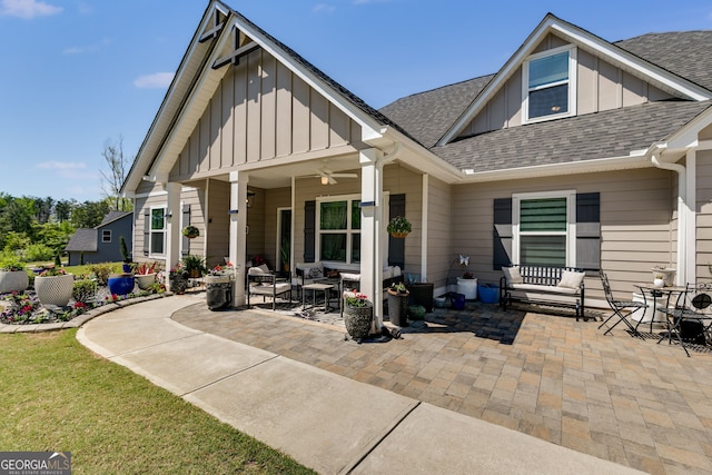 rear view of property with board and batten siding, a patio area, and roof with shingles