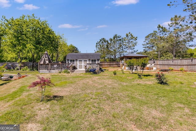 view of yard with a gazebo, a deck, a fenced backyard, an outbuilding, and a storage unit