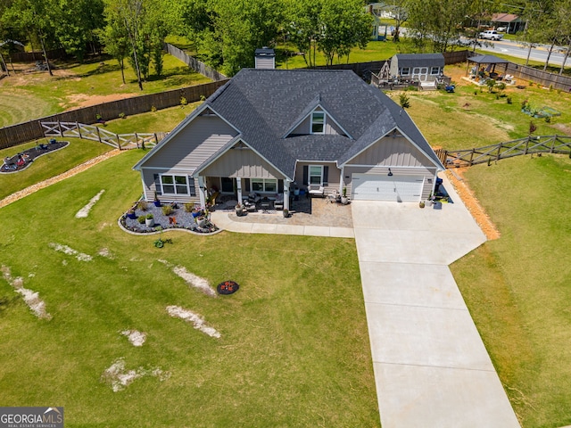 view of front of home with board and batten siding, driveway, a fenced backyard, and a chimney