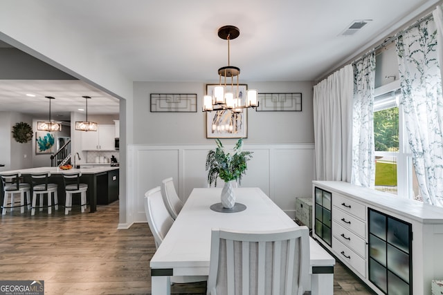 dining area featuring dark wood finished floors, a wainscoted wall, a chandelier, and visible vents