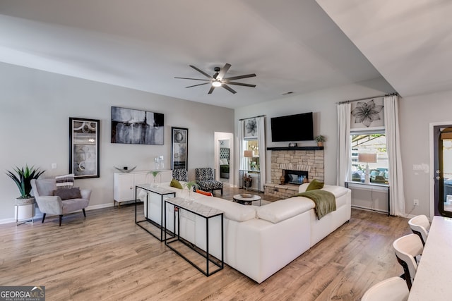 living room with ceiling fan, baseboards, light wood-style flooring, and a fireplace