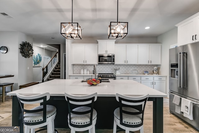kitchen with a sink, visible vents, backsplash, a chandelier, and high end appliances