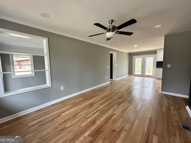 unfurnished living room with visible vents, baseboards, ceiling fan, crown molding, and wood finished floors