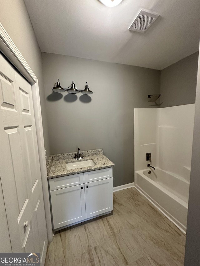 bathroom with visible vents, baseboards, vanity, and tub / shower combination