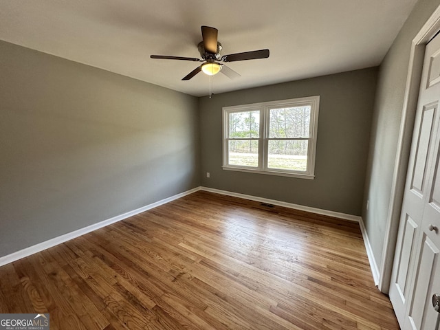 unfurnished room with wood finished floors, baseboards, and a ceiling fan