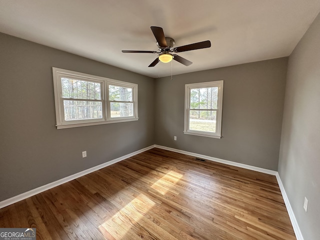 spare room featuring visible vents, baseboards, a ceiling fan, and wood finished floors