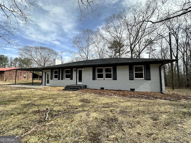 view of front facade with crawl space, a carport, a chimney, and brick siding