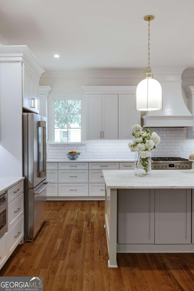 kitchen featuring range, white cabinetry, custom range hood, decorative backsplash, and stainless steel refrigerator