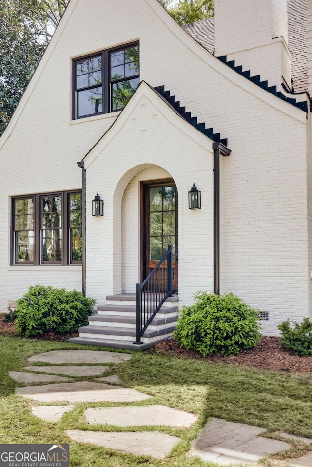 entrance to property featuring a chimney and brick siding
