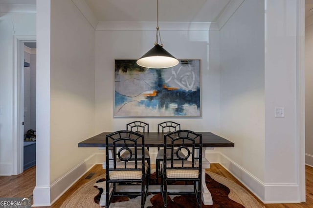 dining space with visible vents, baseboards, ornamental molding, and wood finished floors