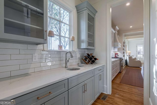 bar featuring tasteful backsplash, visible vents, a healthy amount of sunlight, high end stainless steel range, and a sink