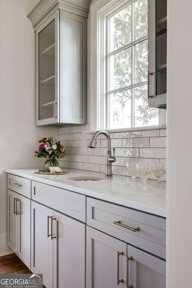 bar featuring tasteful backsplash, dark wood-style floors, and a sink