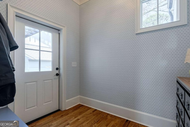 doorway to outside with wallpapered walls, a wealth of natural light, wood finished floors, and baseboards
