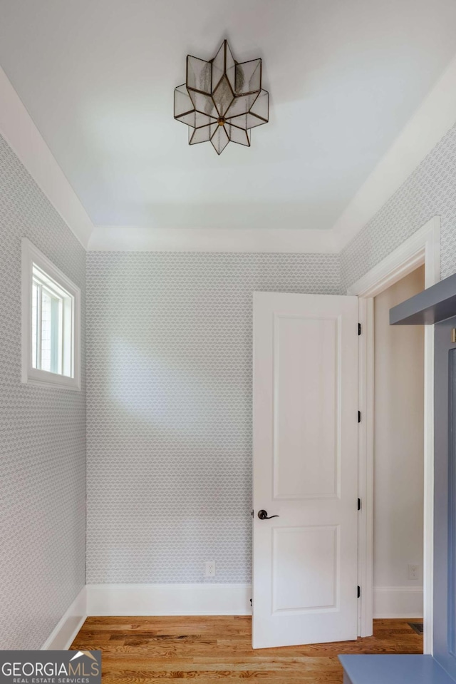 spare room with wood finished floors, baseboards, and wallpapered walls