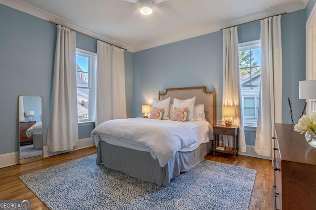 bedroom with baseboards, multiple windows, ceiling fan, and wood finished floors