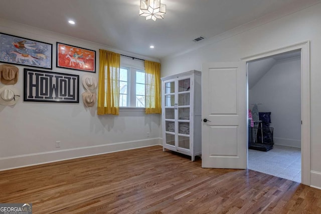 unfurnished room with crown molding, visible vents, baseboards, and wood finished floors
