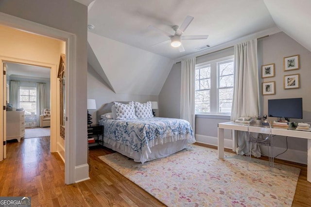 bedroom featuring visible vents, baseboards, a ceiling fan, wood finished floors, and lofted ceiling