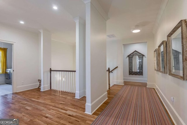 hall featuring an upstairs landing, baseboards, and wood finished floors