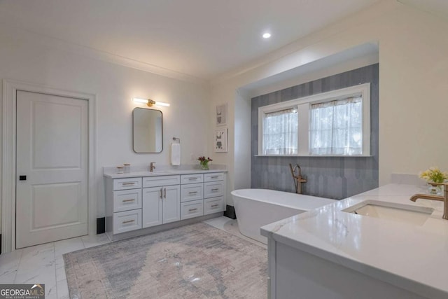 bathroom featuring a soaking tub, two vanities, marble finish floor, and a sink