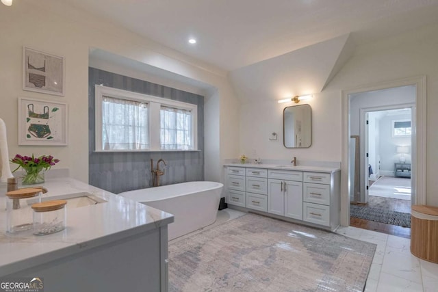 full bath featuring a soaking tub, marble finish floor, plenty of natural light, and vanity