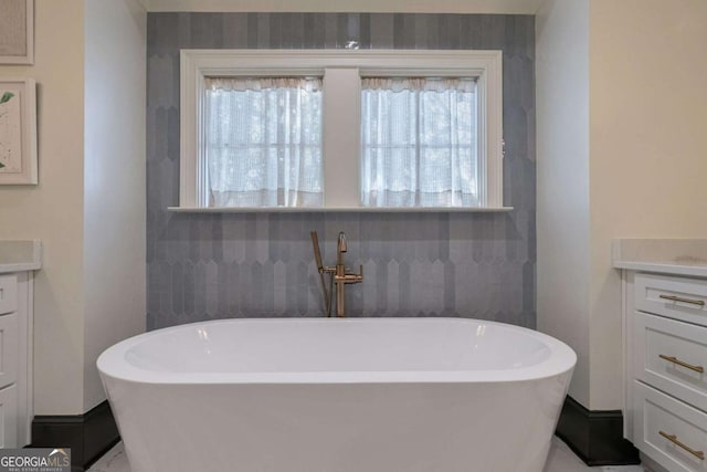 bathroom featuring vanity, baseboards, and a soaking tub